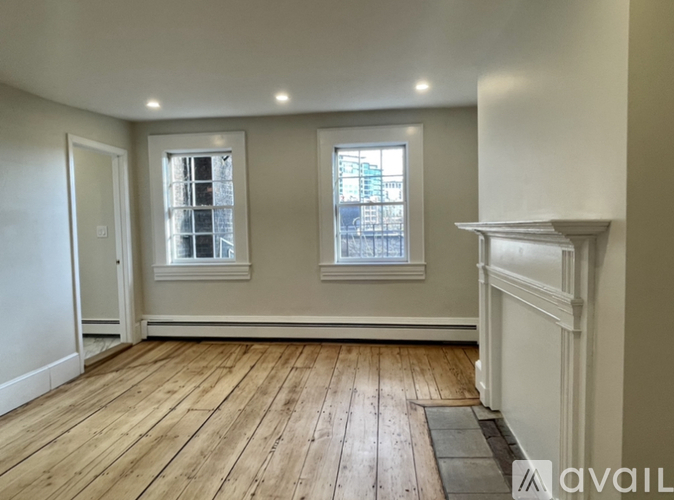 A room with wooden floors and two windows.