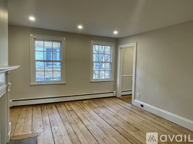 A room with wooden floors and two windows.