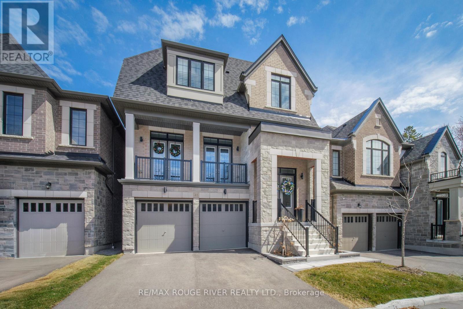 A large, modern house with a grey and stone exterior and a large front yard.