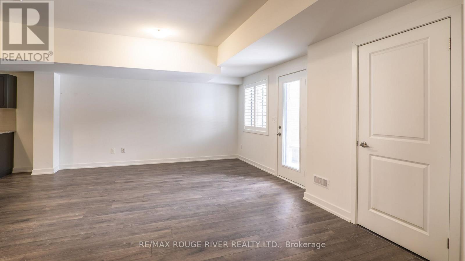 A spacious room with a white door and windows.