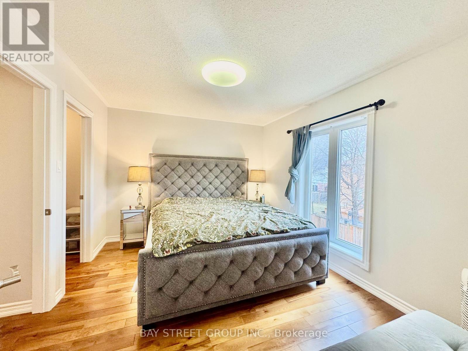 A bedroom with a large bed and a window with curtains.