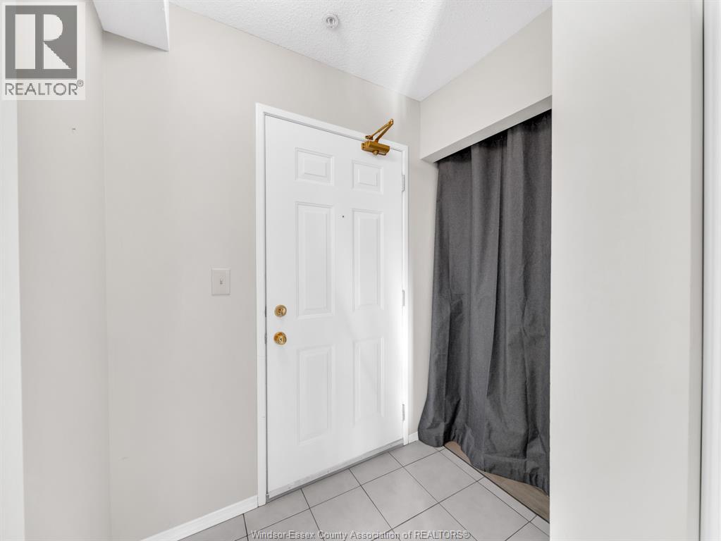A white door with a brass handle is in a room with a grey curtain.