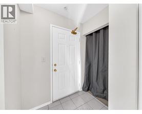 A white door with a brass handle is in a room with a grey curtain.