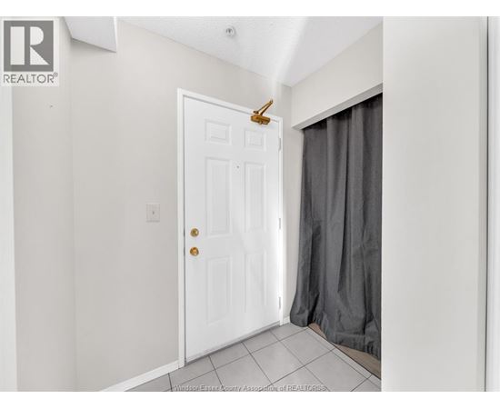 A white door with a brass handle is in a room with a grey curtain.