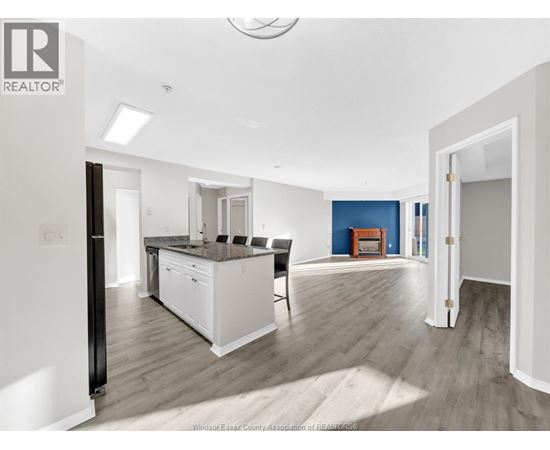 A modern kitchen with white cabinets and a wooden floor.