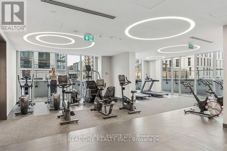 A gym with a variety of equipment and a green exit sign.