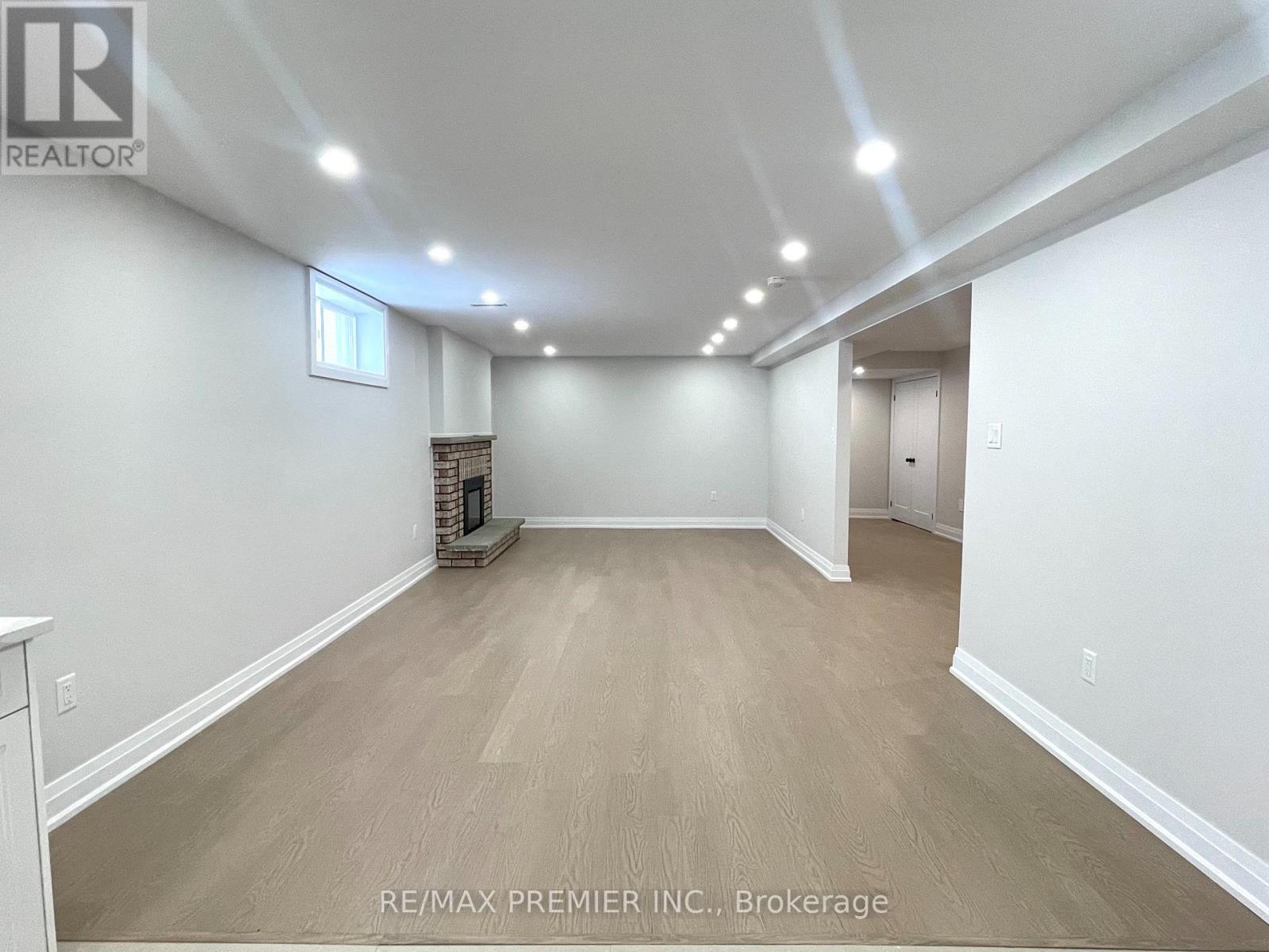 A spacious room with a fireplace and wood flooring.