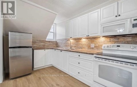 A kitchen with white cabinets and a stainless steel refrigerator.