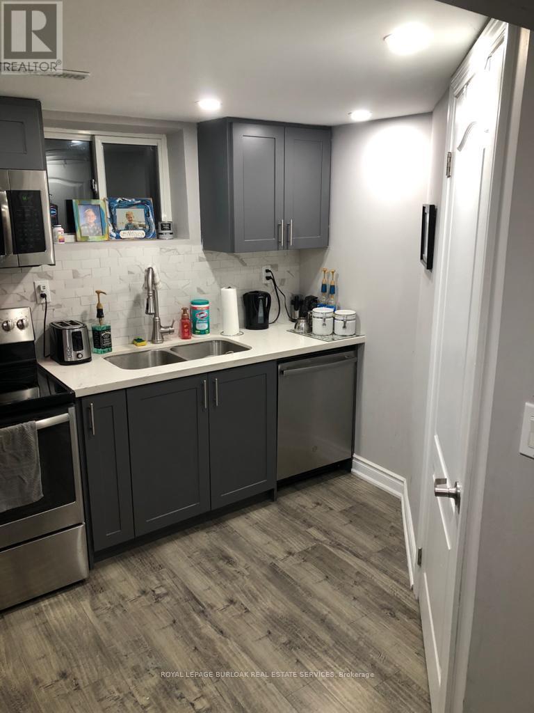 A kitchen with a sink, stove, and cabinets.