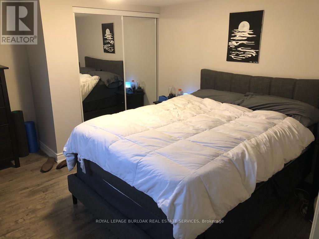A bedroom with a bed, nightstand, and a painting on the wall.