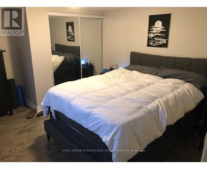 A bedroom with a bed, nightstand, and a painting on the wall.