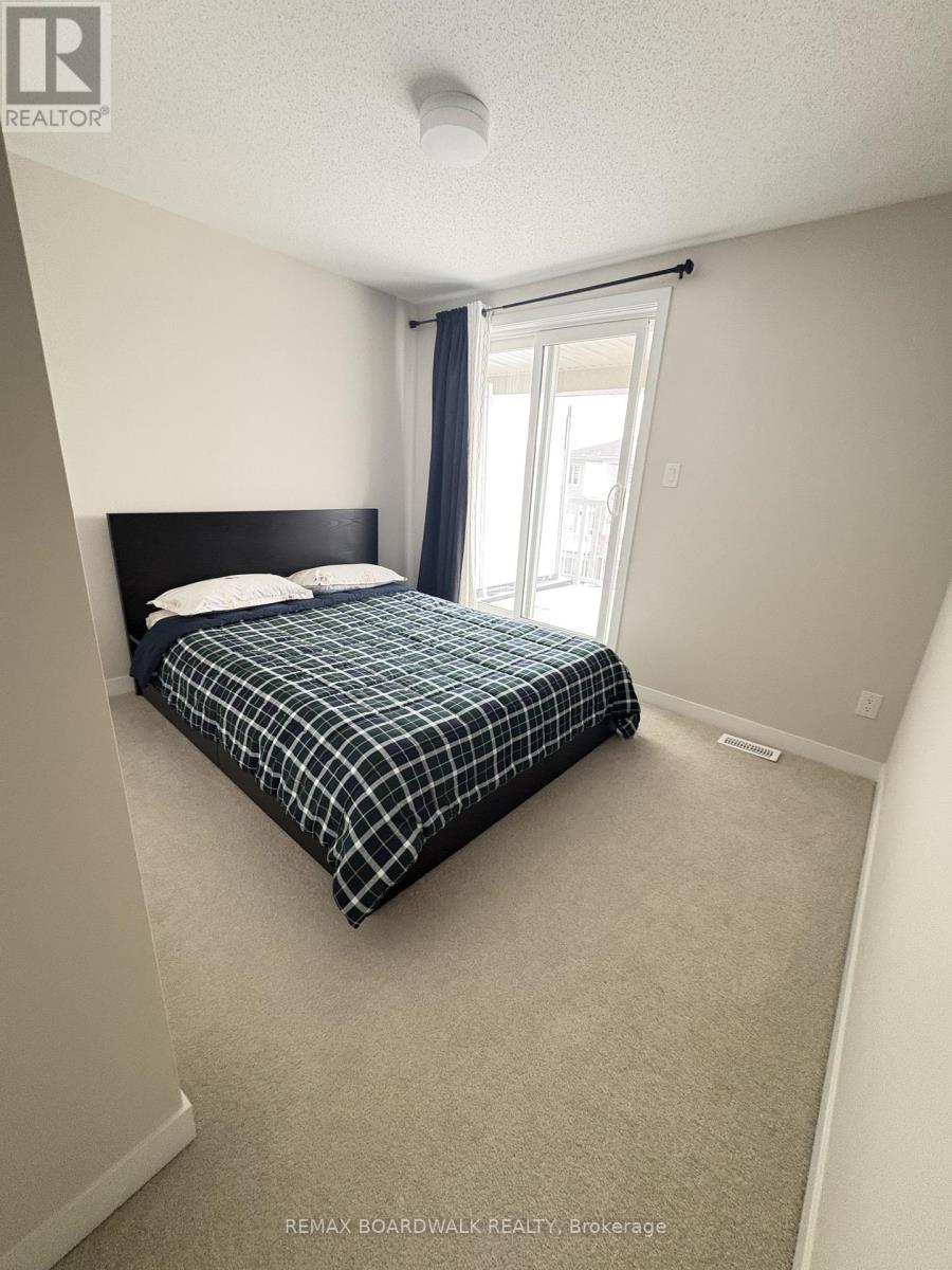 A bedroom with a bed, carpet, and a window.