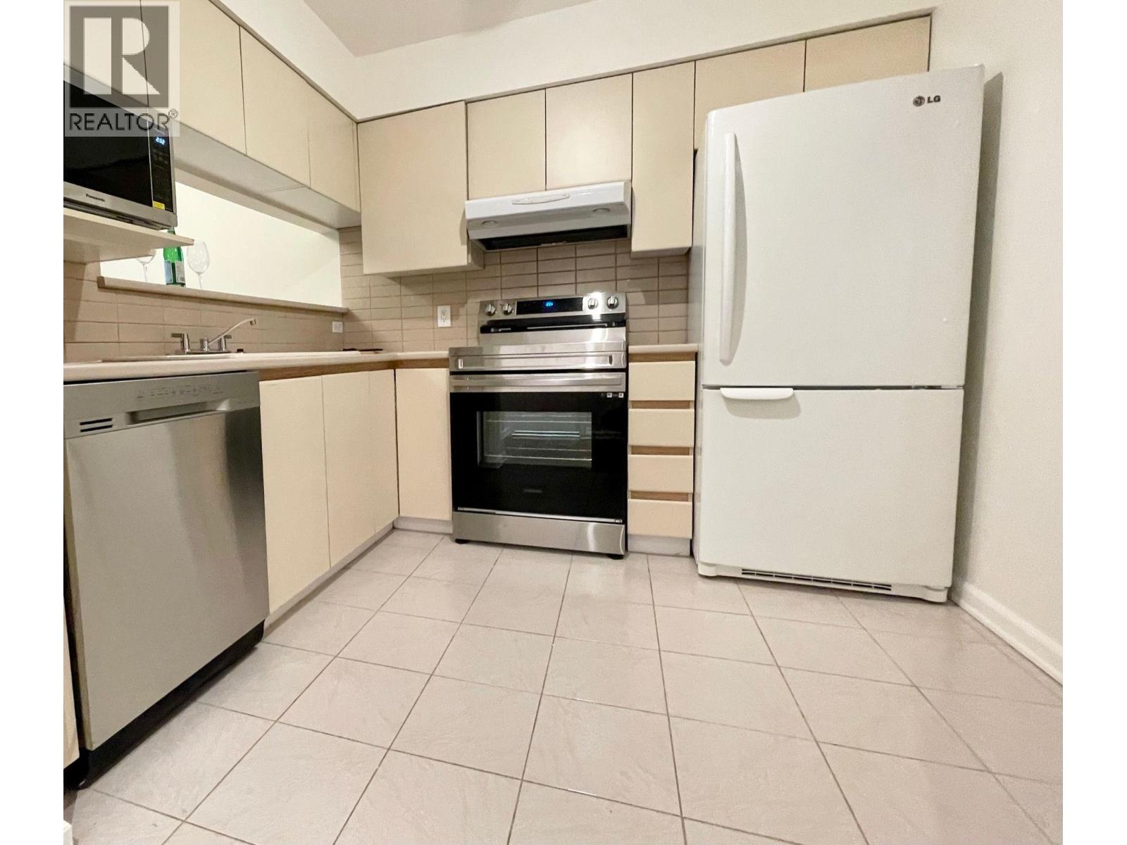 A kitchen with a white fridge, stainless steel dishwasher, and oven.