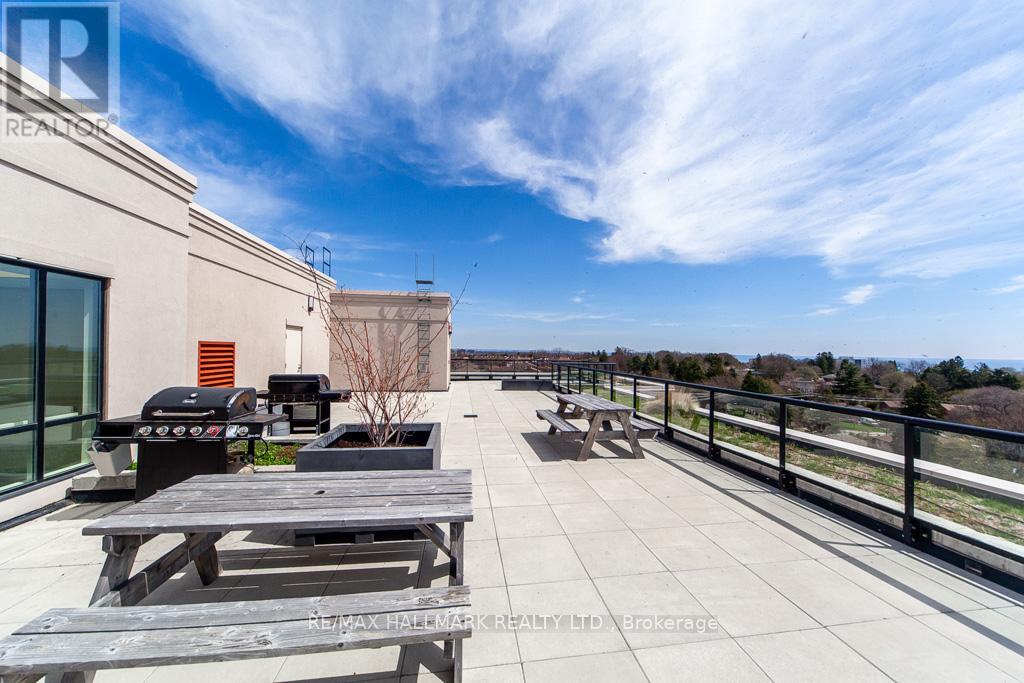 A rooftop patio with picnic tables and a BBQ grill.