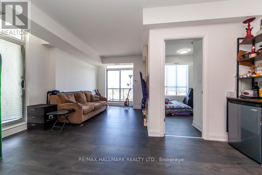 A spacious living room with a brown sofa and a black refrigerator.