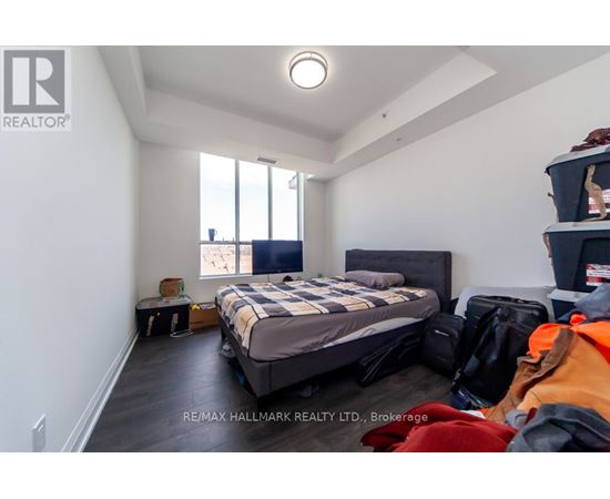 A bedroom with a bed, luggage, and a window.