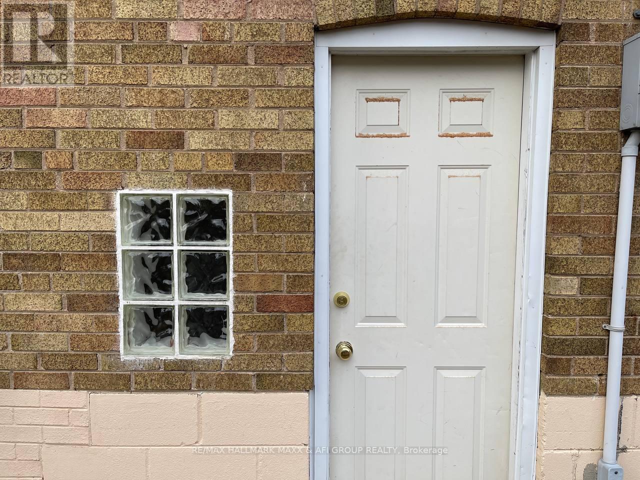 A white door with a window above it on a brick wall.