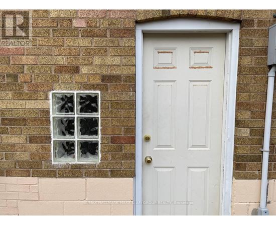 A white door with a window above it on a brick wall.