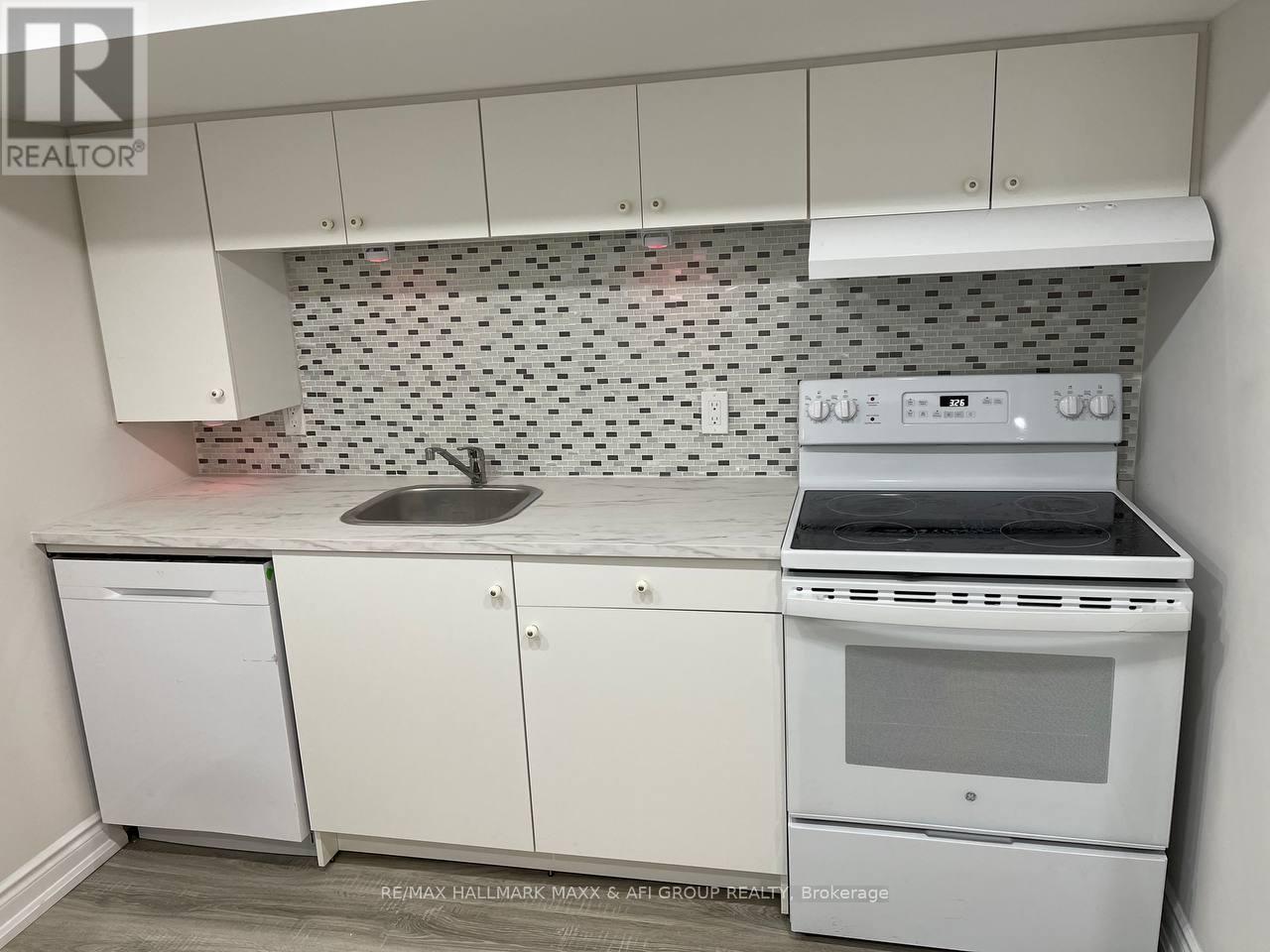 A white kitchen with a Brokerage stove top oven.