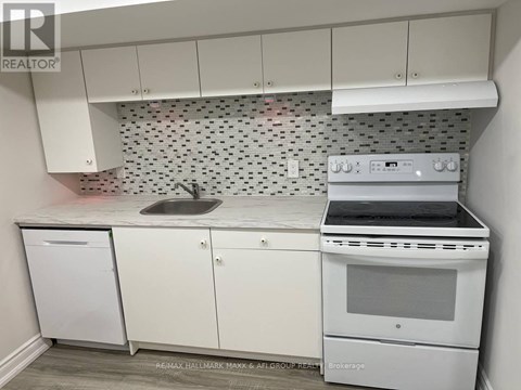 A white kitchen with a Brokerage stove top oven.