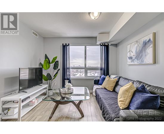 A living room with a grey couch and a glass coffee table.