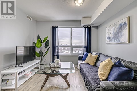 A living room with a grey couch and a glass coffee table.