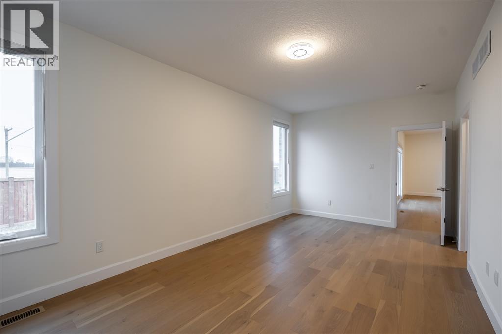 A spacious room with wooden flooring and white walls.
