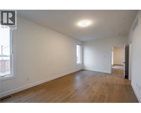 A spacious room with wooden flooring and white walls.