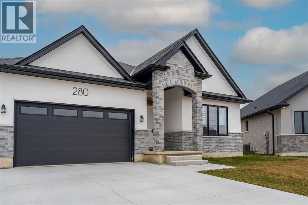 A modern house with a stone pillar entrance and a black garage door.