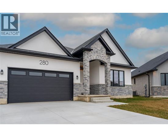 A modern house with a stone pillar entrance and a black garage door.