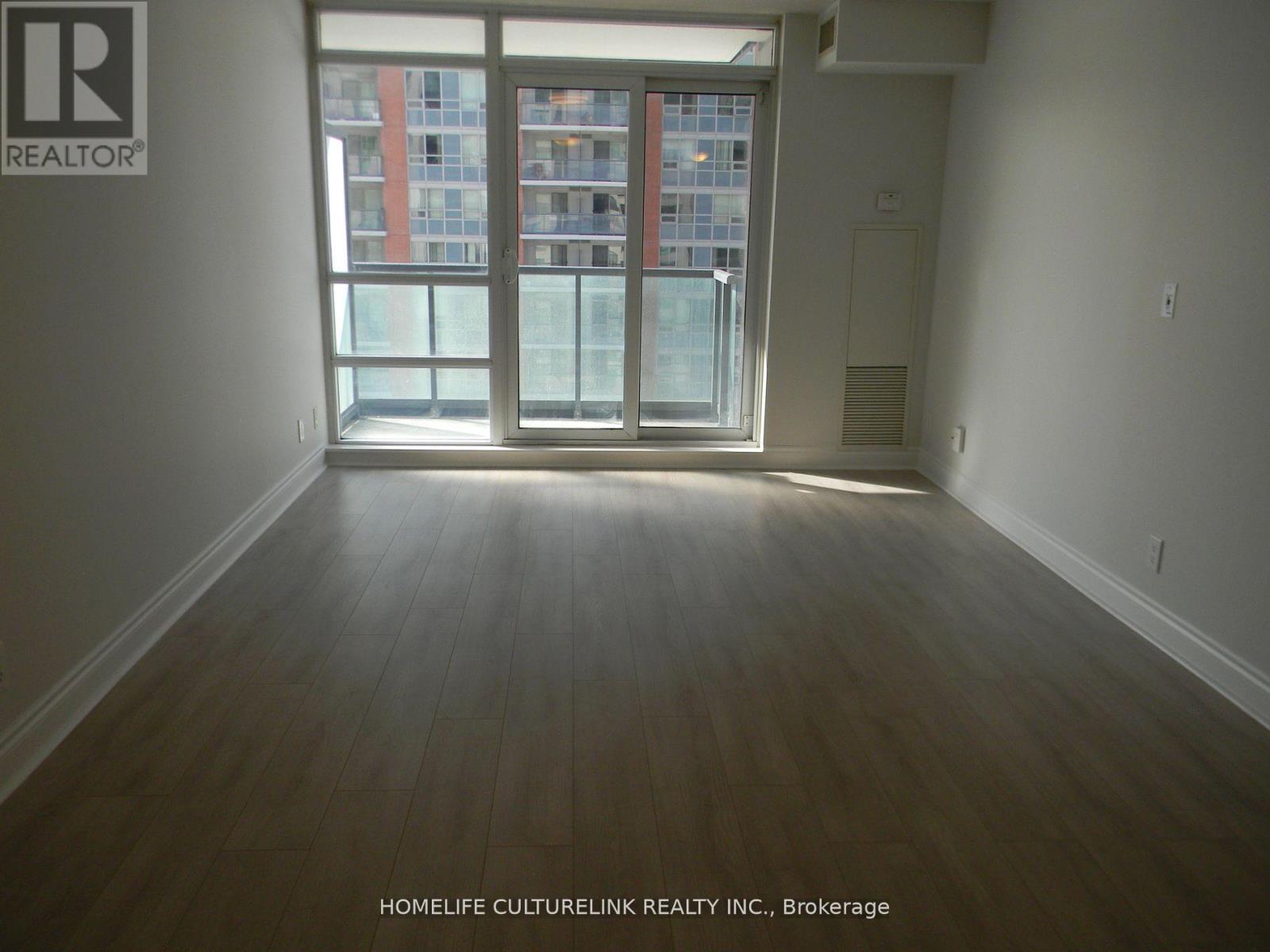 A room with a large window and wooden flooring.