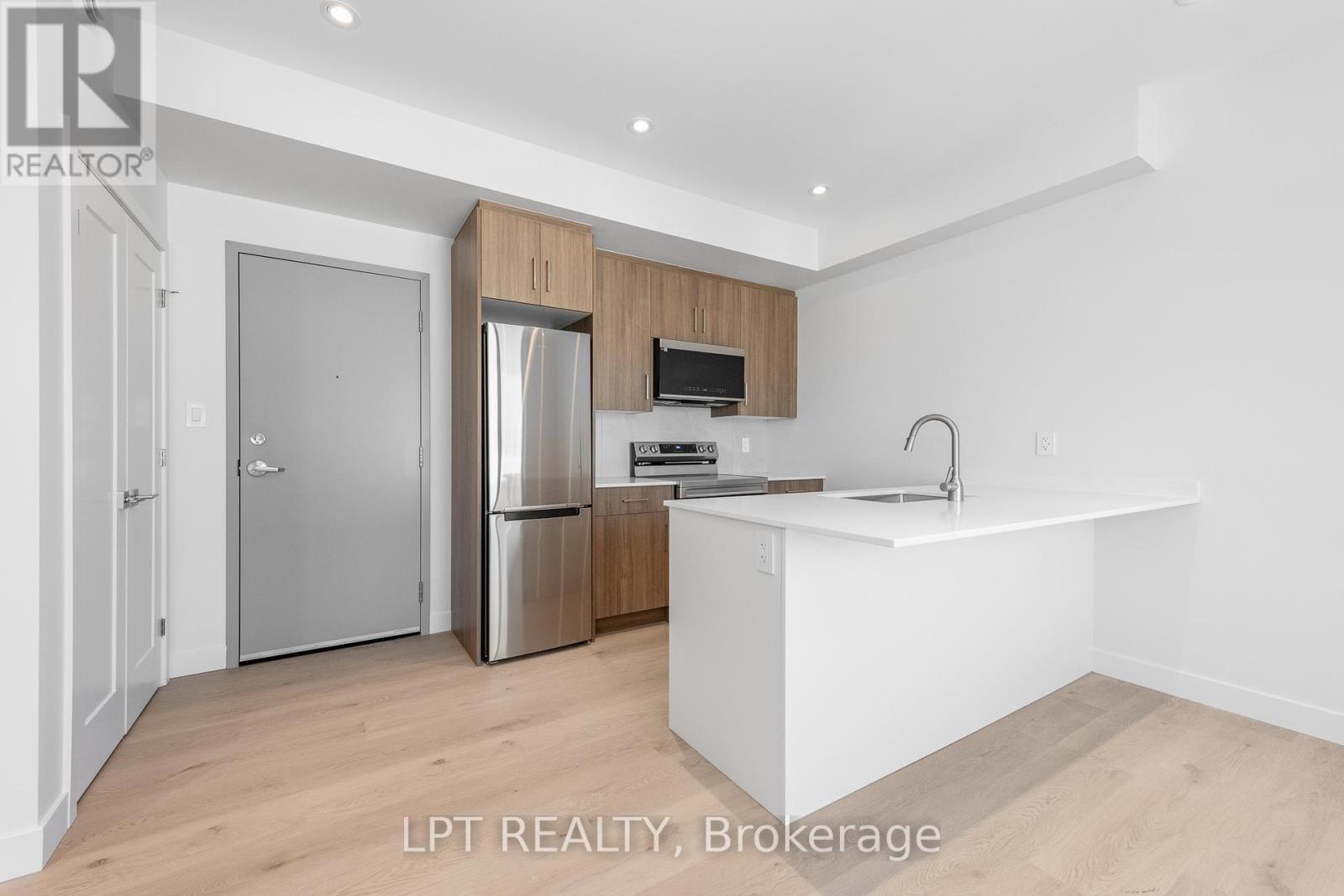 A kitchen with a refrigerator, sink, and cabinets.