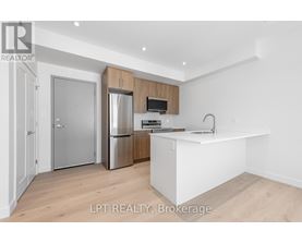 A kitchen with a refrigerator, sink, and cabinets.