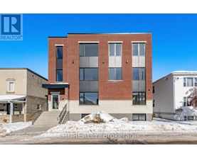 A modern brick building with a glass entrance and a staircase leading to the door.