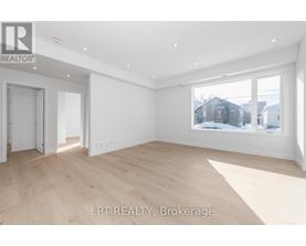 A spacious room with wooden flooring and white walls, with a window showing a snowy landscape outside.