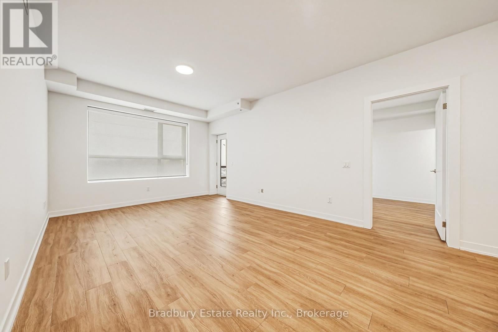 A spacious room with wooden flooring and white walls.