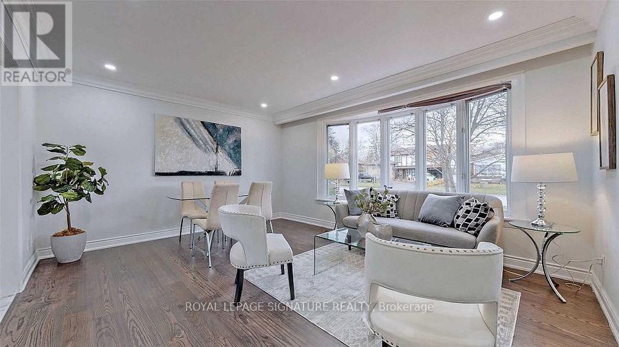 A living room with white furniture and a painting on the wall.
