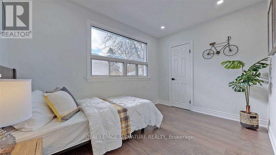 A bedroom with a bed, a plant, and a bicycle on the wall.