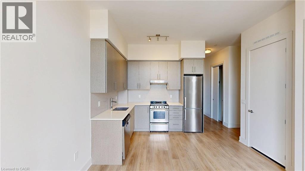 A modern kitchen with wooden floors and stainless steel appliances.