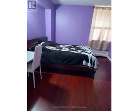 A bedroom with a bed, chair, and purple walls.