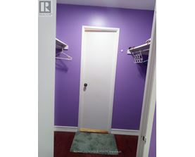 A white door is in a room with purple walls.