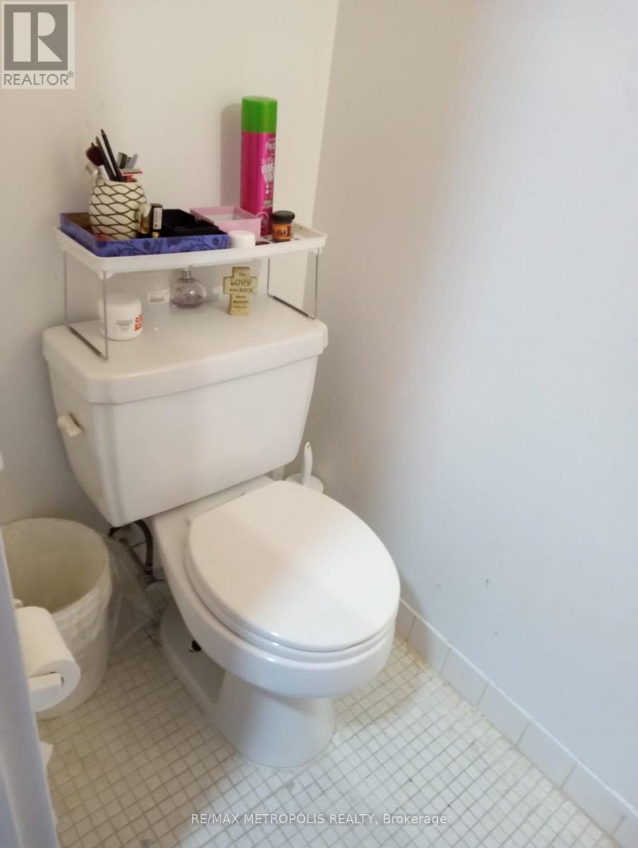 A white toilet with a white tank and a white bathroom.