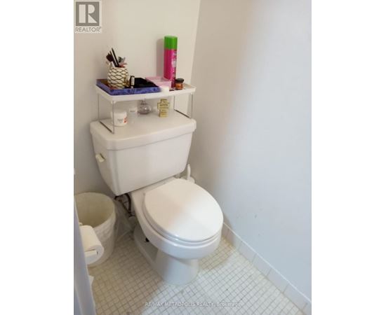 A white toilet with a white tank and a white bathroom.