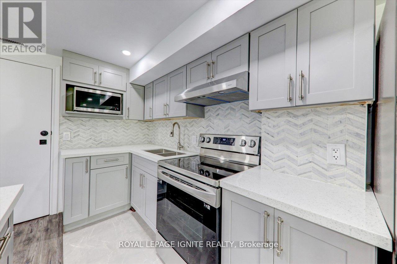 A white kitchen with a stove top oven and a microwave above the fridge.