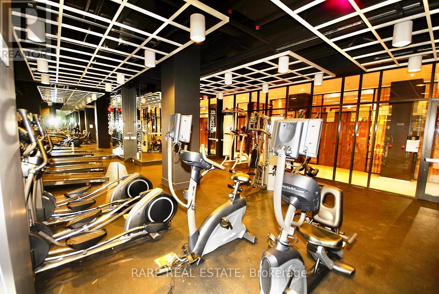 A gym with a row of treadmills and exercise bikes.