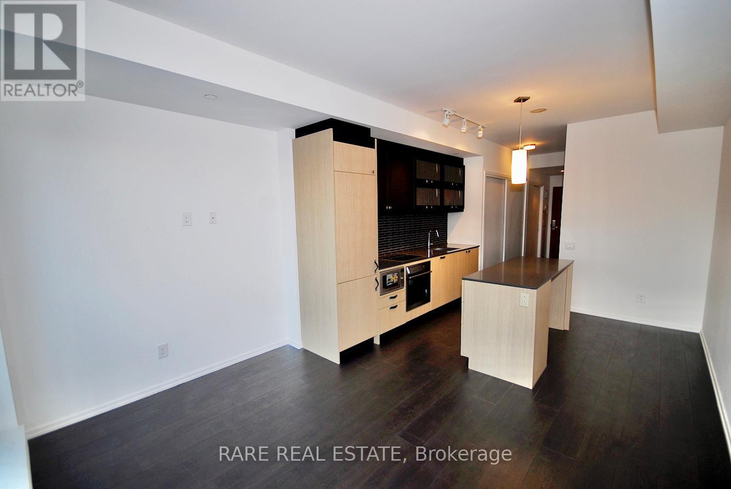 A modern kitchen with wooden cabinets and a black fridge.