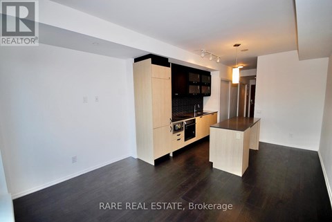 A modern kitchen with wooden cabinets and a black fridge.