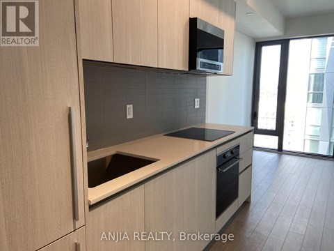A modern kitchen with wooden cabinets and a black countertop.