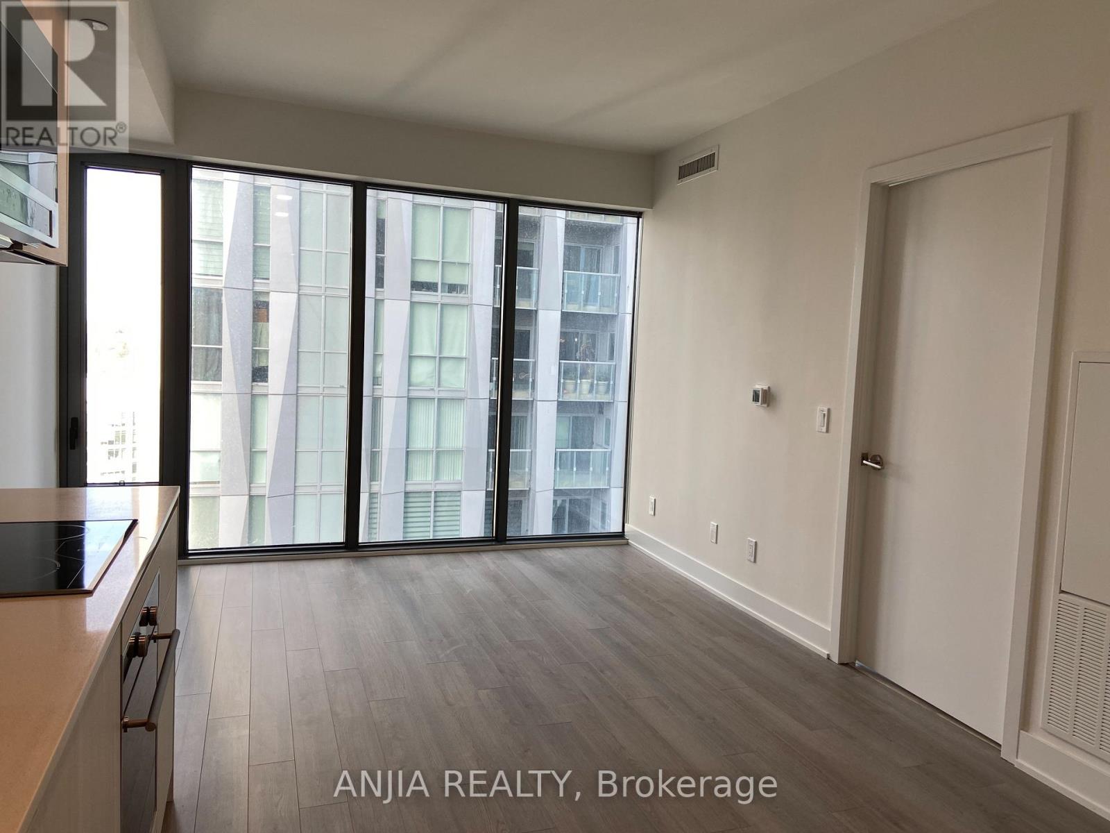 A spacious room with a view of a cityscape through large windows.
