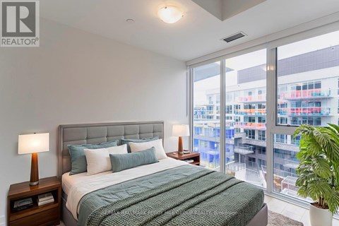 A bedroom with a large bed and a view of a cityscape outside the window.